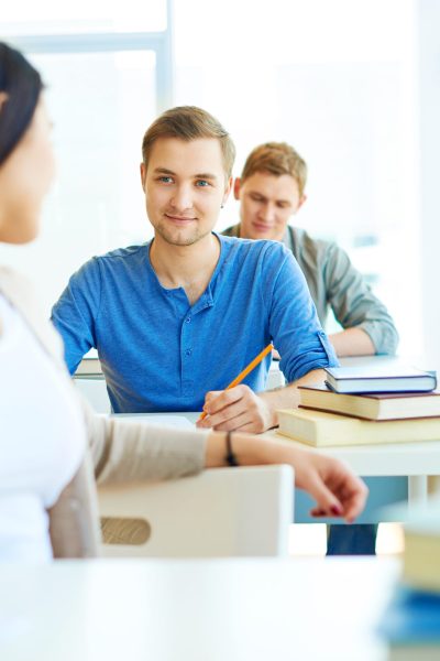 Portrait of smart student consulting his groupmate while carrying out test at lesson
