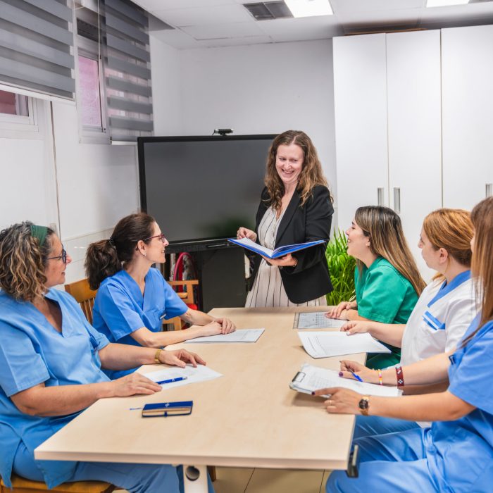 Nurses and a coordinator discuss care strategies in a nursing home, fostering teamwork and communication in a professional setting