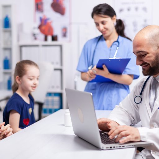Pediatrician doctor and nurse sitting at desk in medical office talking with child. Healthcare practitioner specialist in medicine providing professional radiographic treatment in hospital clinic