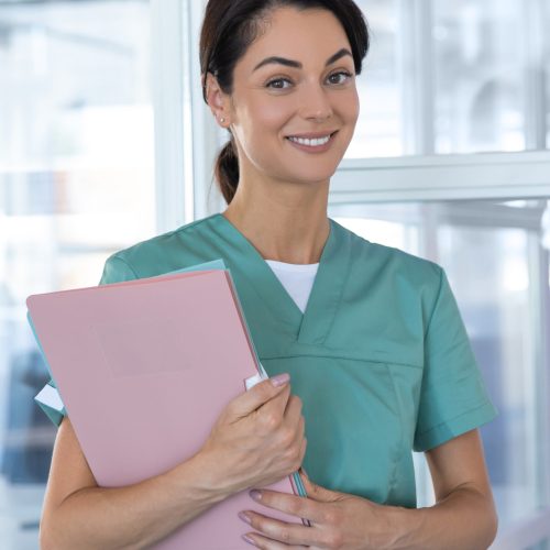 Happy doctor. Pretty smiling young woman in lab coat looking contented